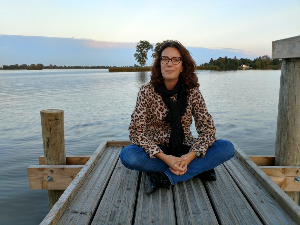 Natalie zittend op een aanlegsteiger aan een meer